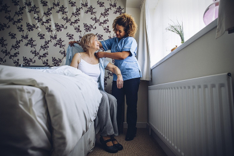 Caregiver Helping a Senior Woman Get Dressed